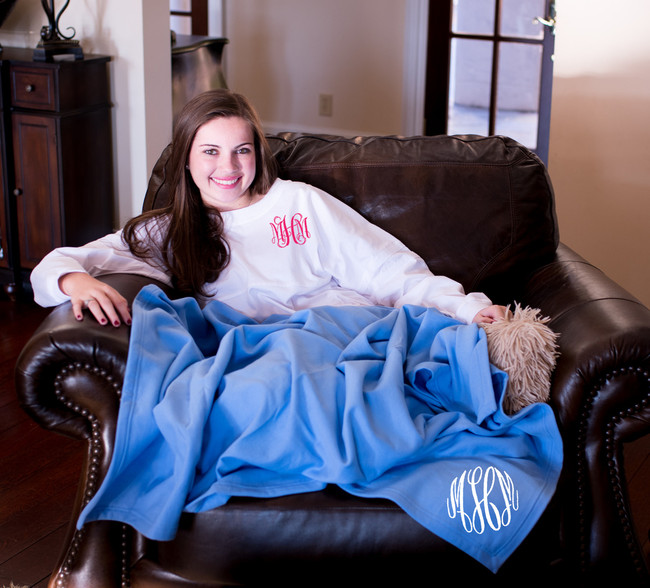 A young woman with a monogrammed shirt and blanket